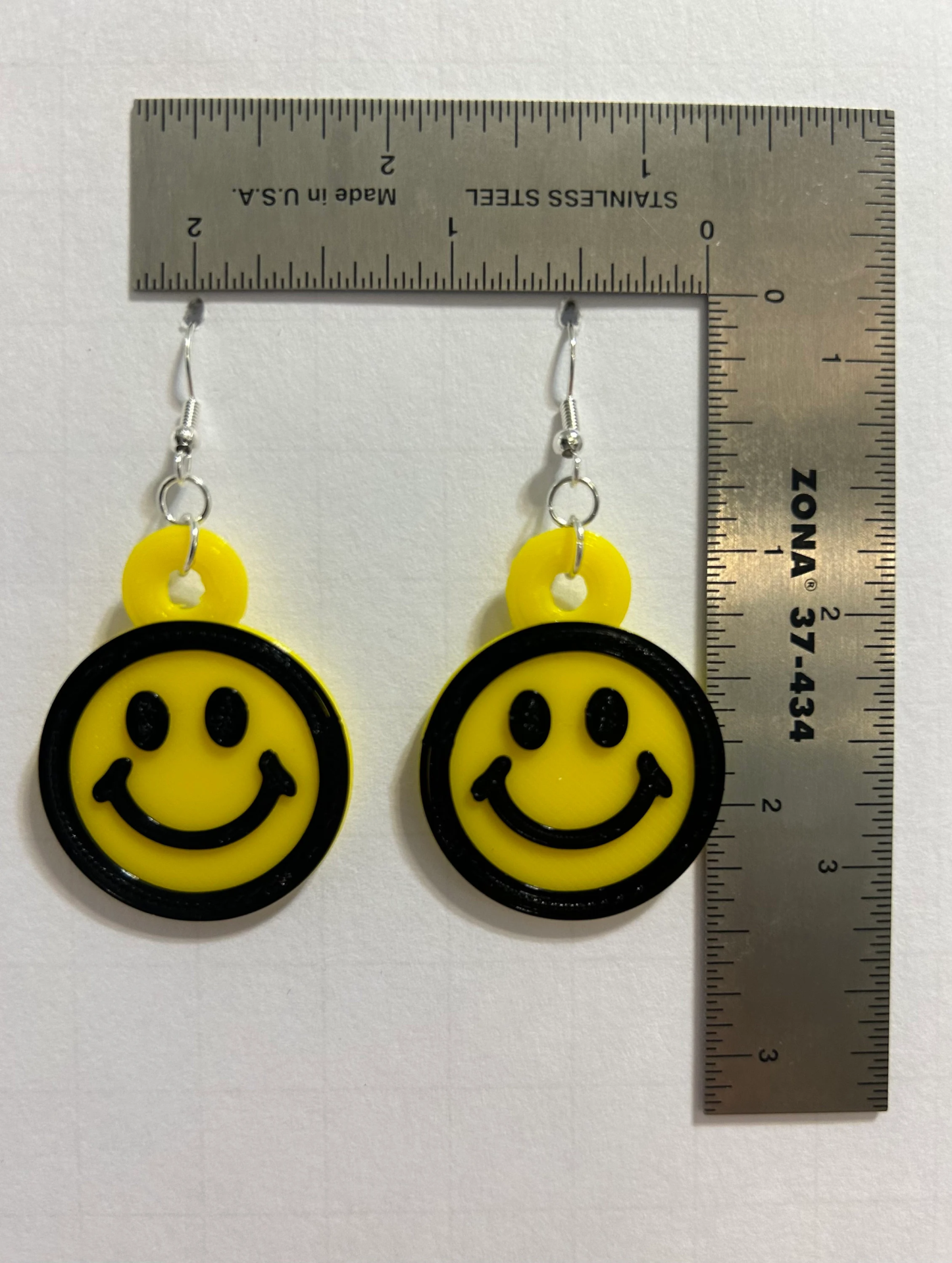 Pair of round yellow smiley face earrings with cheerful expressions.