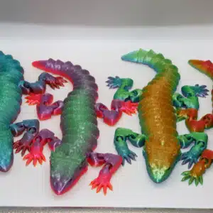 Articulated bearded dragon fidget toy in unique rainbow and camo color variations displayed on a flat surface