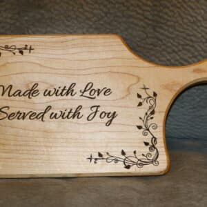 Maple charcuterie board with engraved leafy border and customizable text displayed on a kitchen counter
