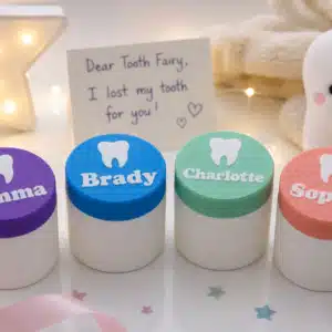 Personalized Tooth Fairy Boxes with white containers and custom colored lids featuring children's names and a raised tooth design in purple, blue, mint green, and pink.